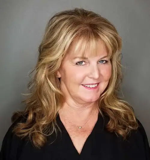 Lange Wellen mit abgerundetem Pony Stufig fransige Frisuren für Frauen ab 50 die jünger machen