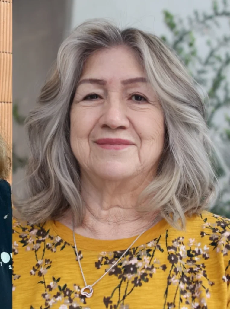 Frau über 60 mit Bob und Curtain Bangs, silbergraues schulterlanges Haar mit weichen Wellen für einen modernen und jugendlichen Look.
