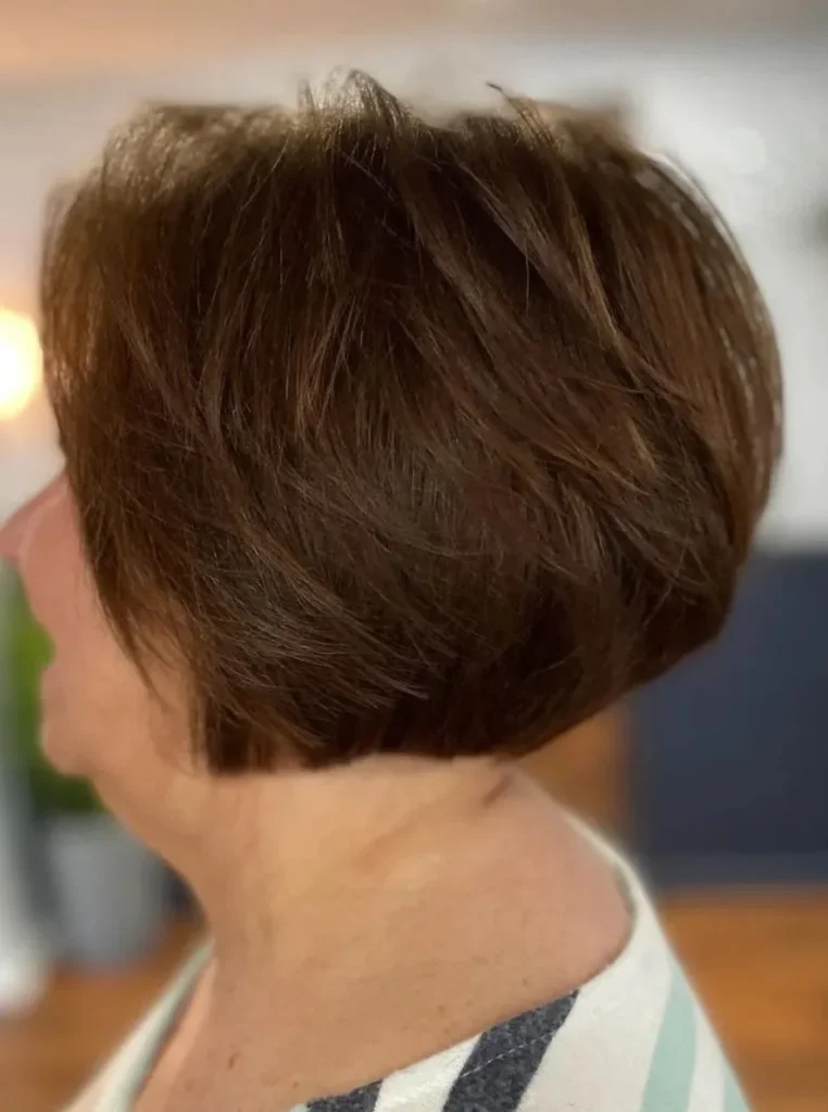 Frau über 60 mit Bob Frisur und Volumen am Hinterkopf, dunkelbraunes Haar mit gestuften Partien für mehr Fülle und einen eleganten Look.