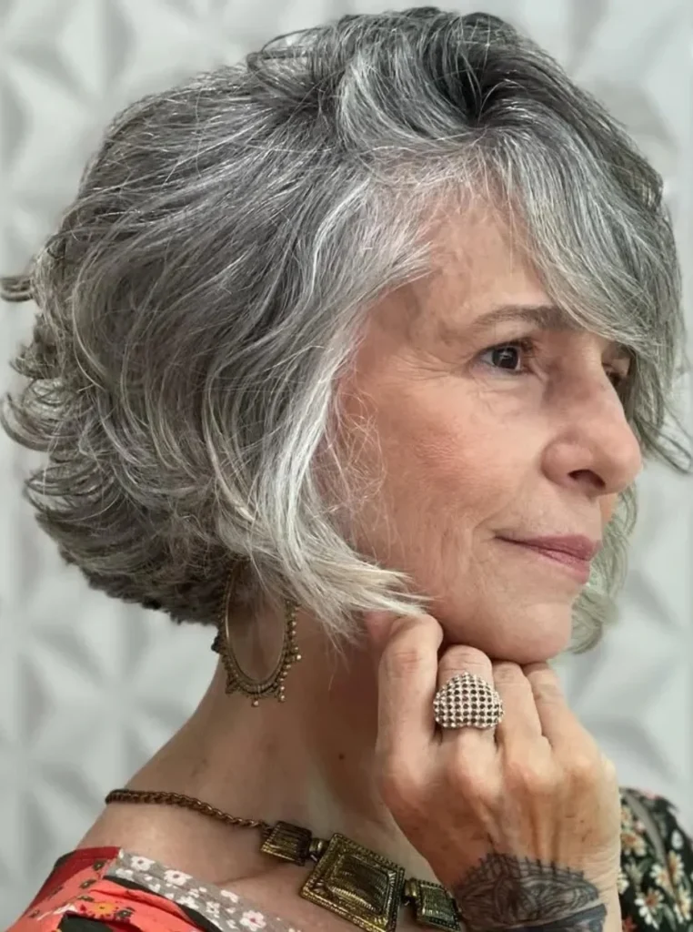 Frau über 60 mit Choppy Bob in Silbergrau, texturierter Bob mit federnden Stufen und viel Volumen für einen modernen und jugendlichen Look.