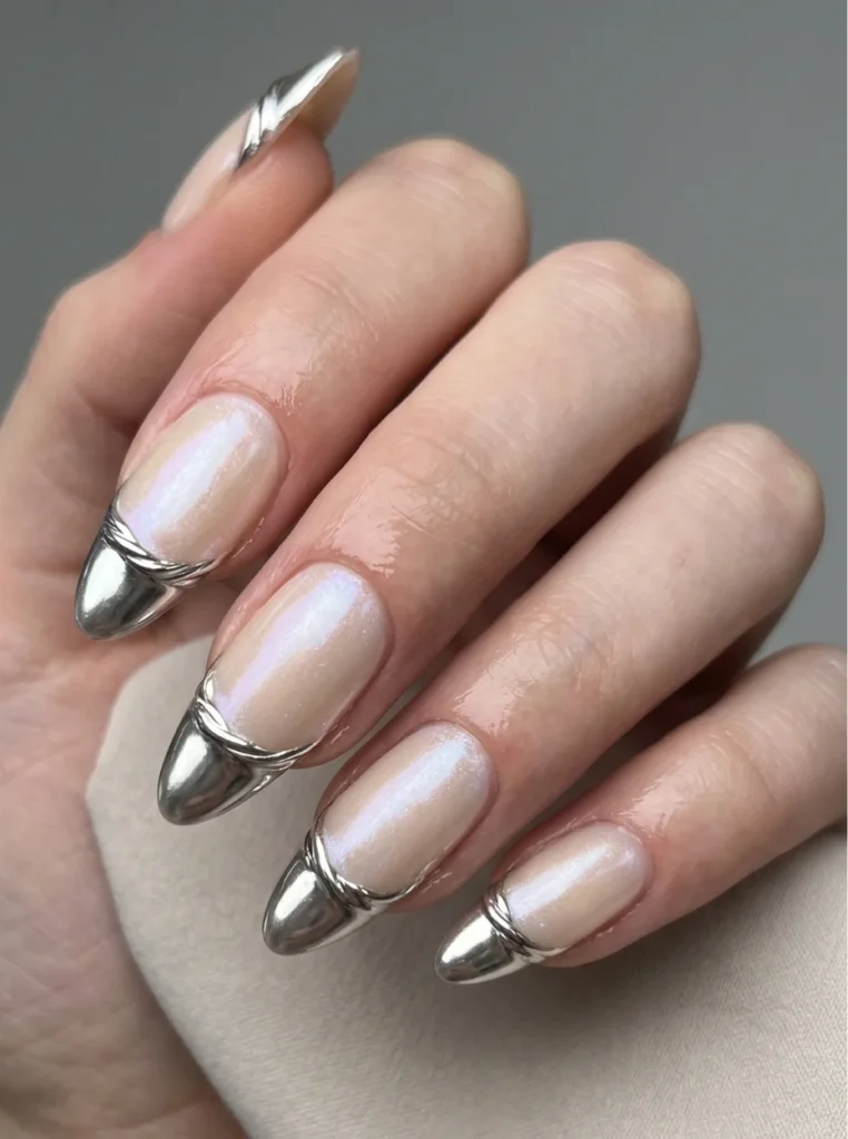 Moderne Chrome French Nägel mit silbernen Metallic-Spitzen und schimmernder Nude-Basis auf langen mandelförmigen Nägeln in eleganter Nahaufnahme