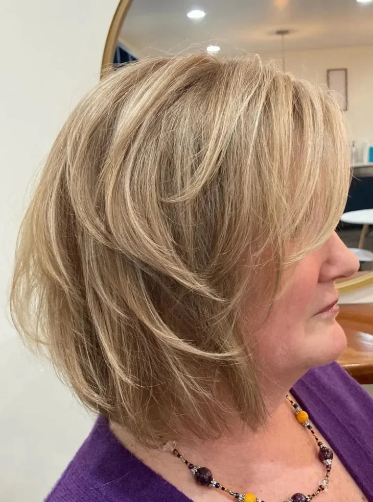 Frau über 60 mit gestuftem Bob und langem seitlichem Pony, voluminöse Frisur mit weichen Stufen für einen modernen und jugendlichen Look.