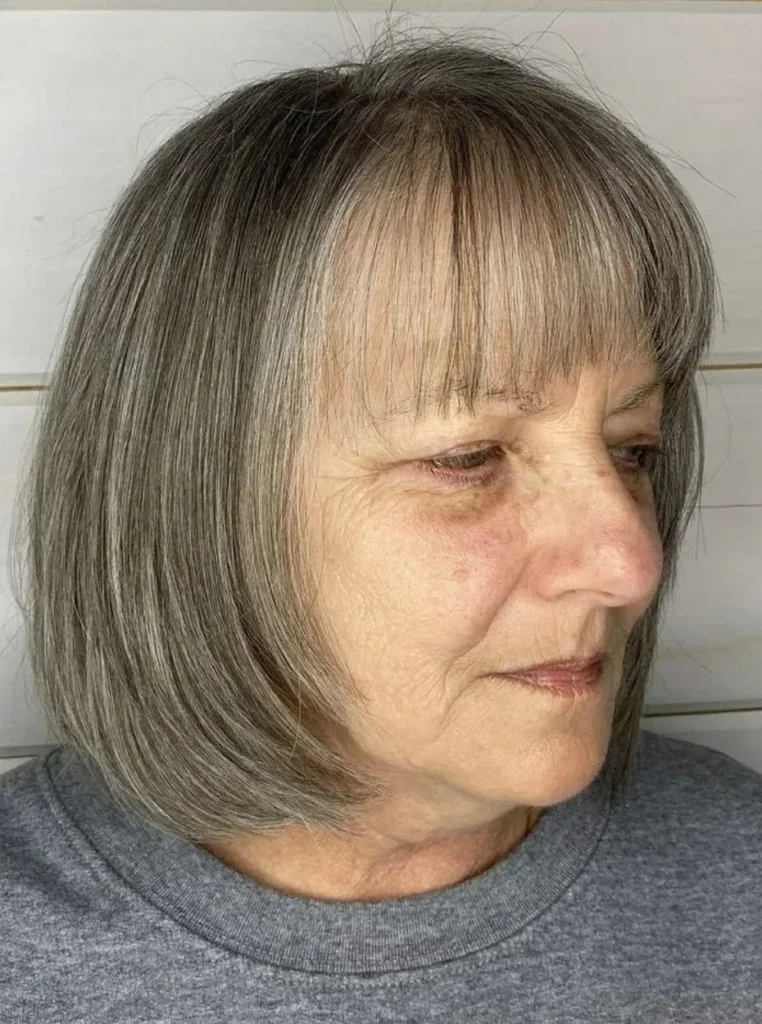 Frau über 60 mit kinnlangem Bob, grauem Haar und feinem Pony, klassische Bob Frisur für einen eleganten und zeitlosen Look.