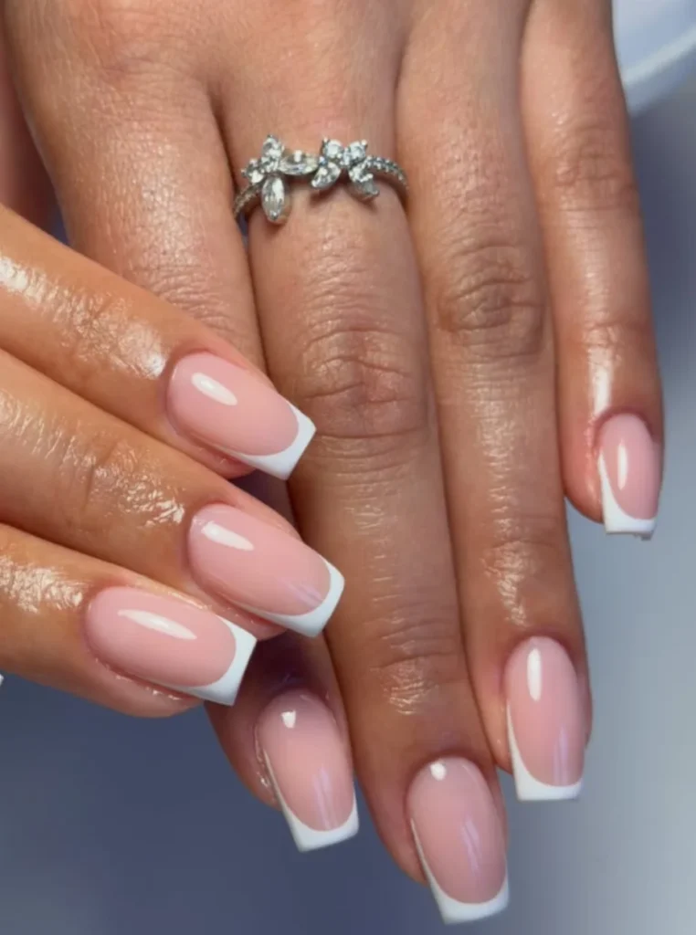 Klassische weiße French Nails mit glänzendem Nude-Finish und eleganten square Nagelspitzen in modernem Design.