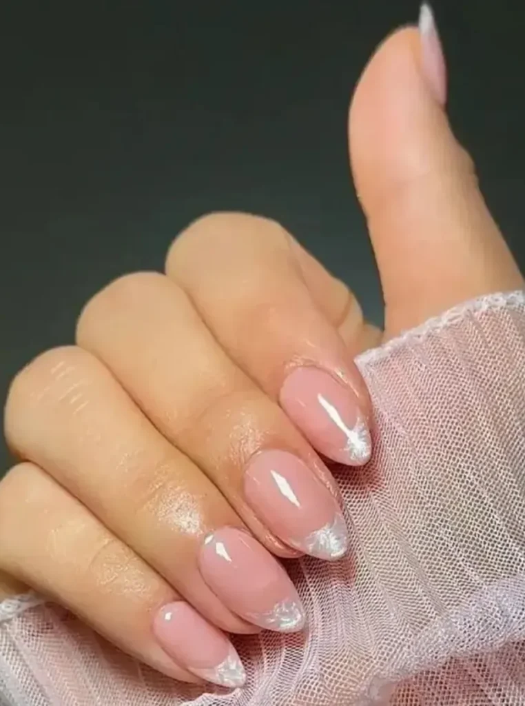 Milchig-weiße französische Nägel mit glänzendem Finish und eleganten Perlspitzen auf mandelförmigen Nägeln.