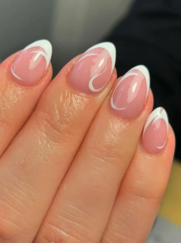 Moderne milky French Nägel mit glänzender rosa Nude-Basis und geschwungenen weißen Spitzen auf kurzen eleganten Nägeln.
