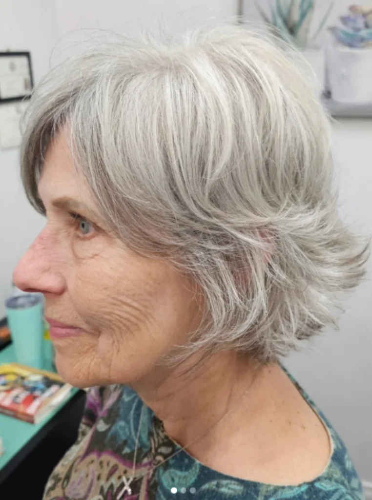 Frau über 60 mit natürlich texturiertem Bob in Silbergrau, federnde Stufen und voluminöse Haarstruktur für einen modernen und jugendlichen Look