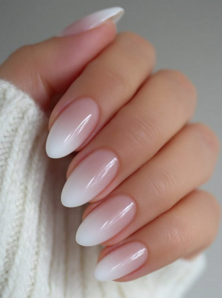 Ombre weiße French Nägel mit sanftem Farbverlauf und glänzendem Nude-Finish auf eleganten mandelförmigen Nägeln.