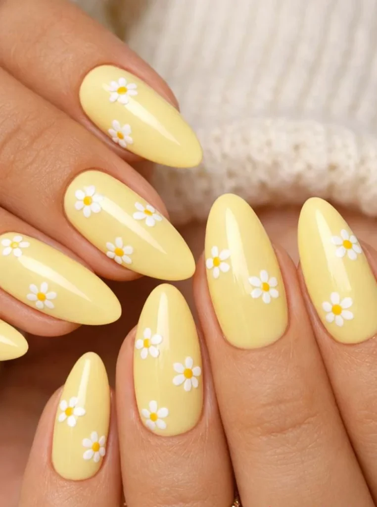 Pastellgelbe Almond Nägel mit Gänseblümchen und glänzendem Finish