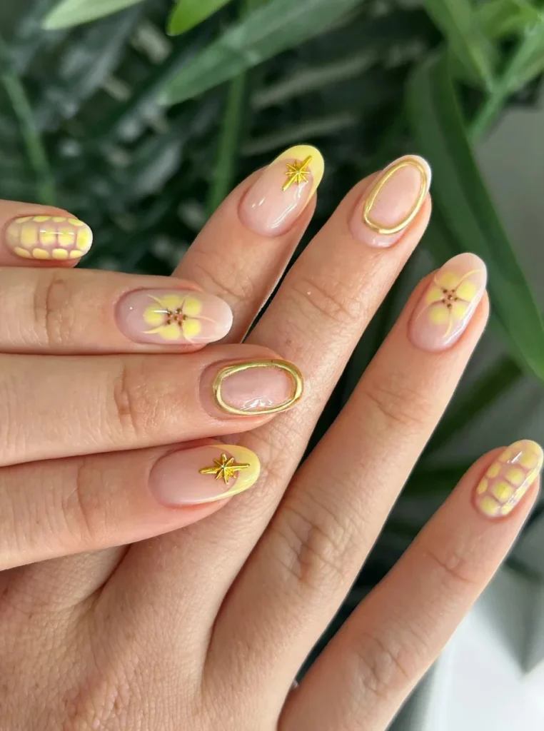 Pastellgelbe Nägel mit goldenen Akzenten, Blumen und elegantem Design