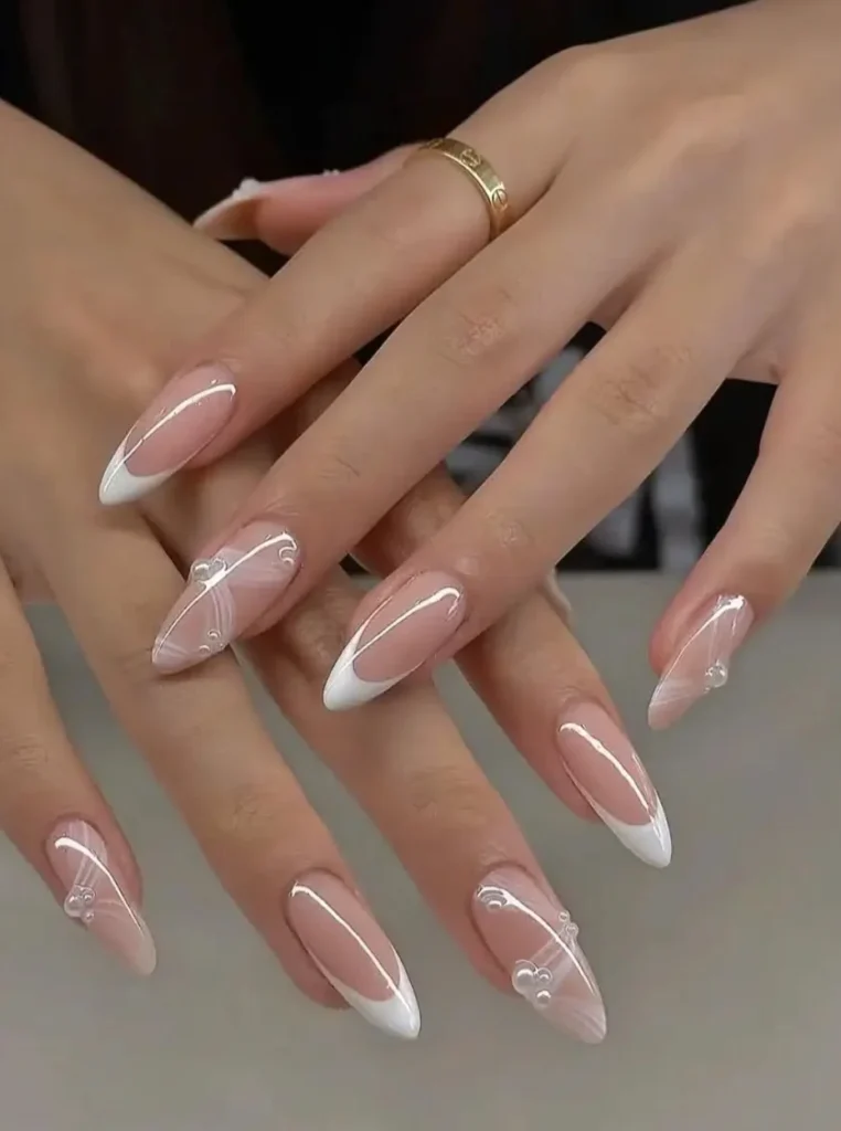 Pearl weiße French Nägel mit eleganten weißen Spitzen, zarten Perl-Details und glänzendem Nude-Finish auf langen mandelförmigen Nägeln.