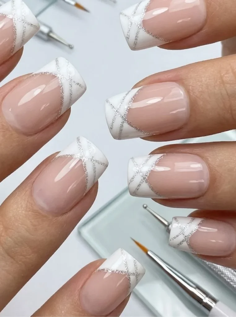 Quadratische weiße French Nägel mit feinen silbernen Glitzerlinien und glänzendem Nude-Finish in elegantem modernem Design.