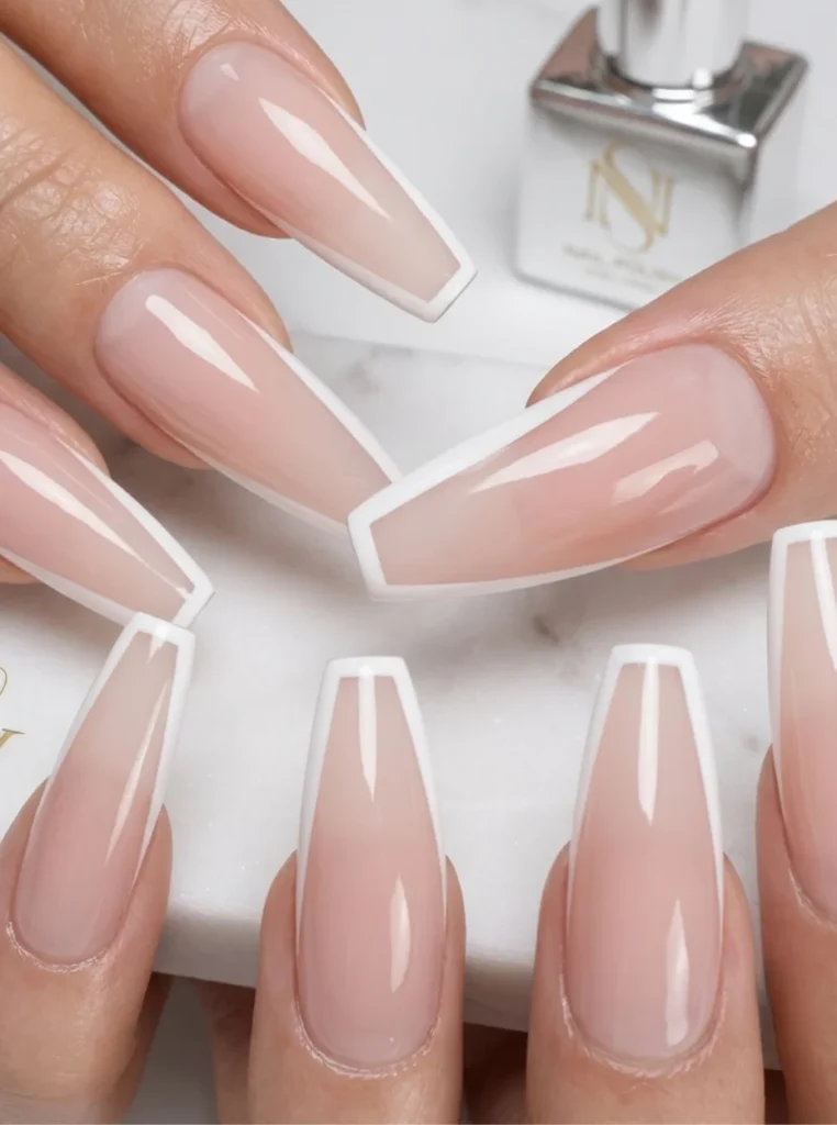 Sargform weiße French Nägel mit glänzendem Nude-Finish und modernen weißen Spitzen auf langen Coffin-Nägeln.