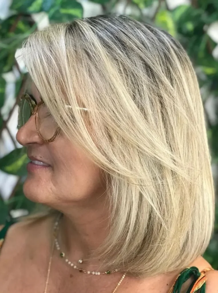 Frau über 60 mit schulterlangem Bob, blondem Haar und sanften Stufen für mehr Volumen, Bewegung und einen eleganten Look.