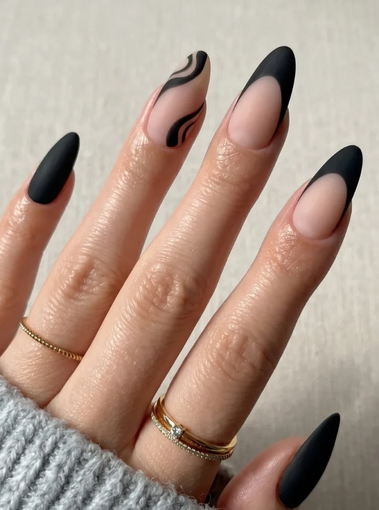 Moderne schwarze French Nägel mit matten Spitzen und Nude-Basis auf mandelförmigen Nägeln in eleganter Nahaufnahme.