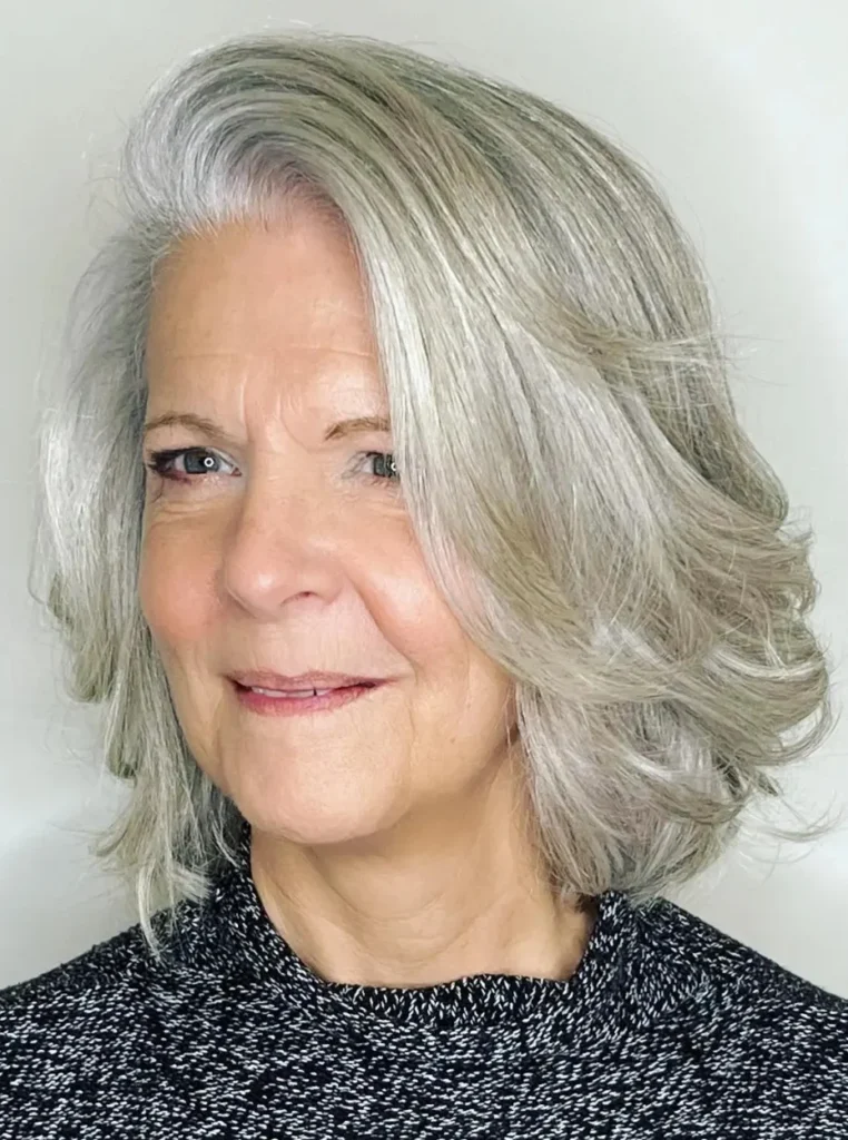 Frau über 60 mit silbernem Bob, voluminösem grauem Haar und weichen Stufen für einen eleganten, modernen und jugendlichen Look.