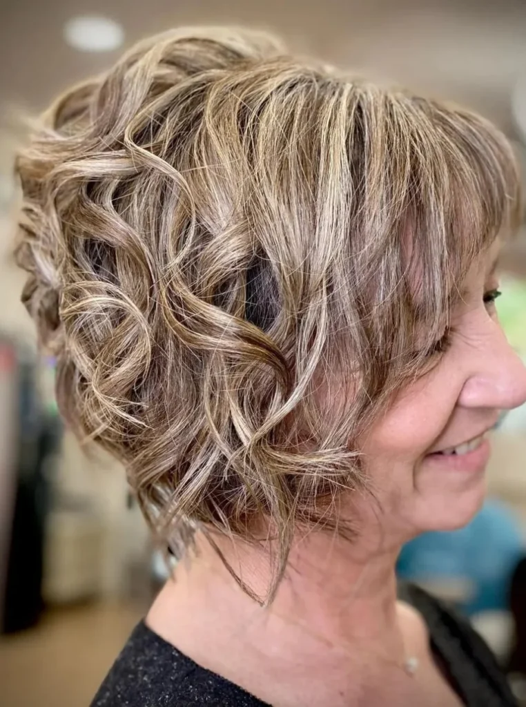 Frau über 60 mit Wellen-Bob, weichen Locken und blonden Highlights, voluminöse Bob Frisur für einen modernen und jugendlichen Look.