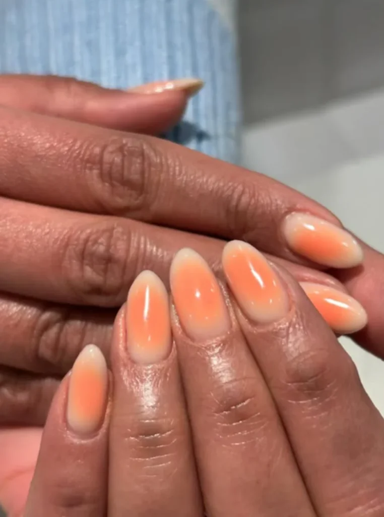 Apricot Aura Nägel mit sanftem Ombre-Effekt auf mandelförmigen Nägeln in einem modernen und natürlichen Design.