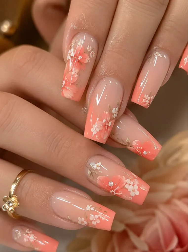 Apricot Blumen Nägel mit zarten weißen Blüten auf langen Coffin-Nägeln und glänzendem Nude-Aproncot-Verlauf.