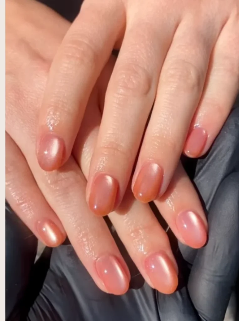 Apricot Cat Eye Nägel mit schimmerndem Magneteffekt auf kurzen ovalen Nägeln und glänzendem Finish.