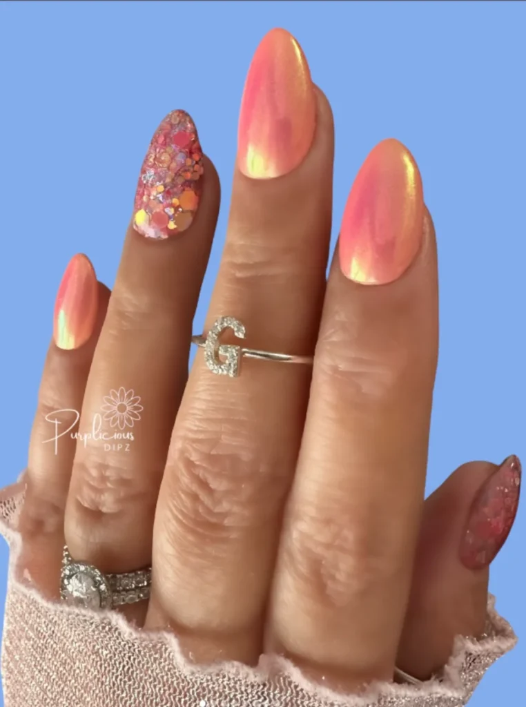 Apricot Chrome Nägel mit schimmerndem Perleffekt und glitzerndem Akzentnagel in Mandelform.