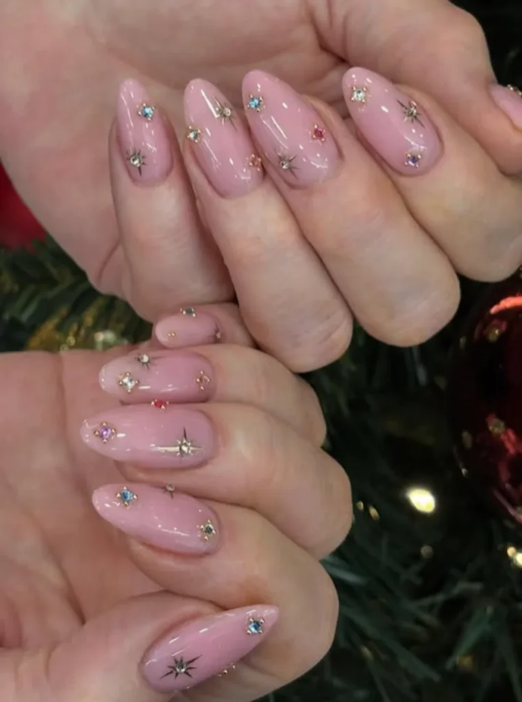 Babyrosa Nägel mit funkelnden Strasssteinen und Stern-Details auf mandelförmigen Nägeln – elegante und trendige Sommer-Maniküre.