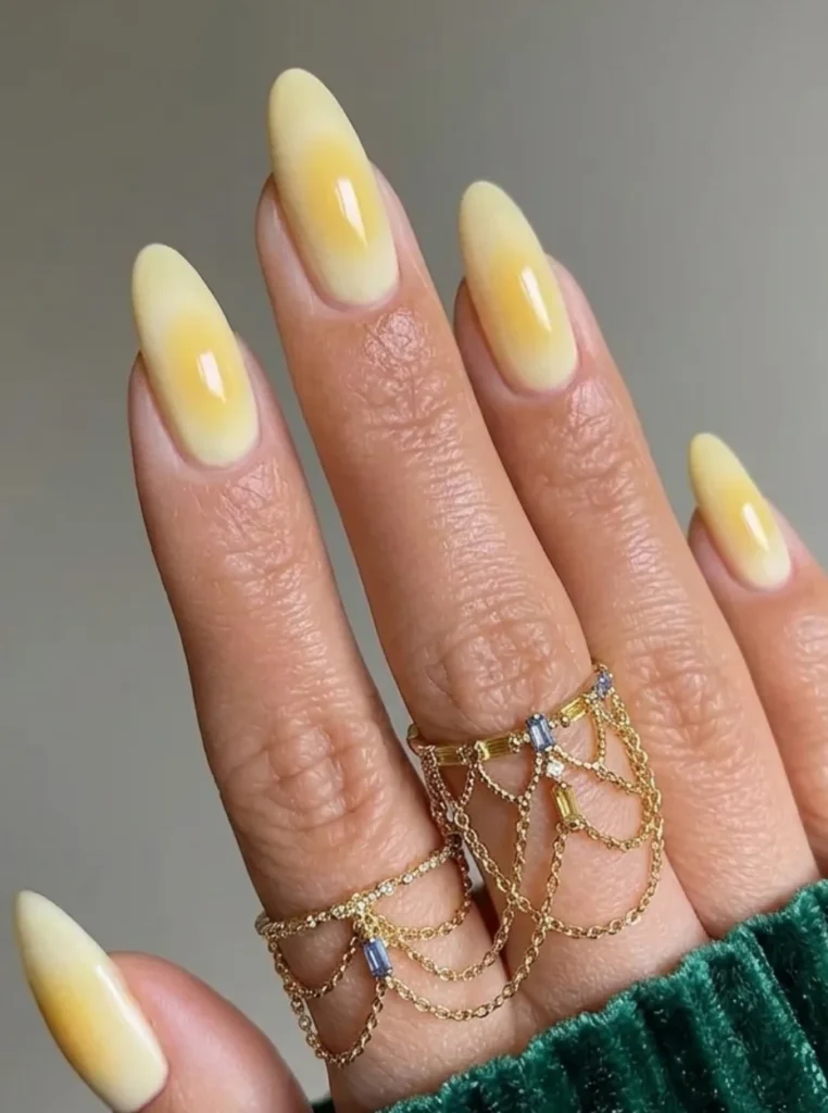 Butter Yellow Aura Nails mit weichem gelbem Glow-Effekt auf mandelförmigen Nägeln – modernes Nageldesign