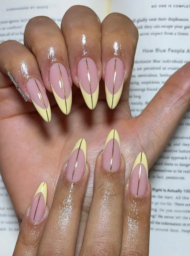 Butter Yellow Nägel mit feinen Goldlinien und eleganten French Tips auf mandelförmigen Nägeln