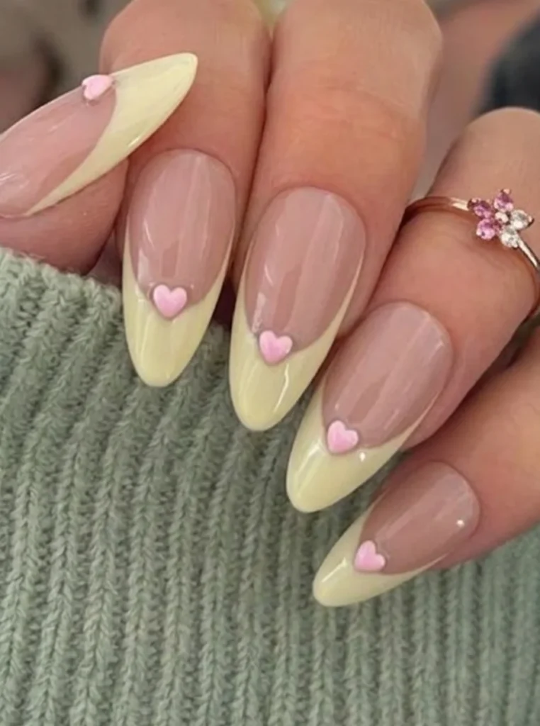 Butter Yellow Nägel mit rosa Herzmotiven und French Tips auf mandelförmigen Nägeln – romantisches Nageldesign