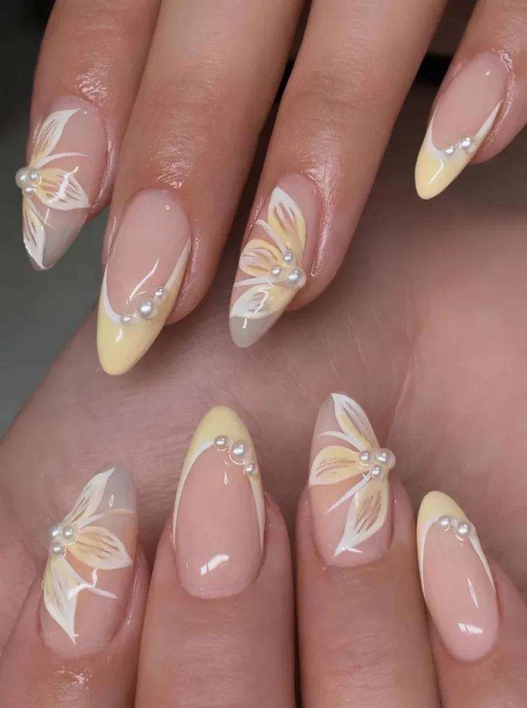 Butter Yellow Nägel mit Perlen, floraler Nail Art und eleganten French-Spitzen auf mandelförmigen Nägeln