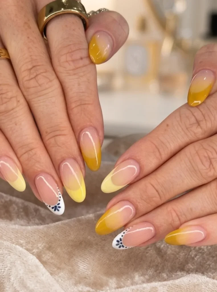Gelb French Nägel mit sanftem Farbverlauf in verschiedenen Gelbtönen, glänzender Nude-Basis und eleganten mandelförmigen Nägeln.