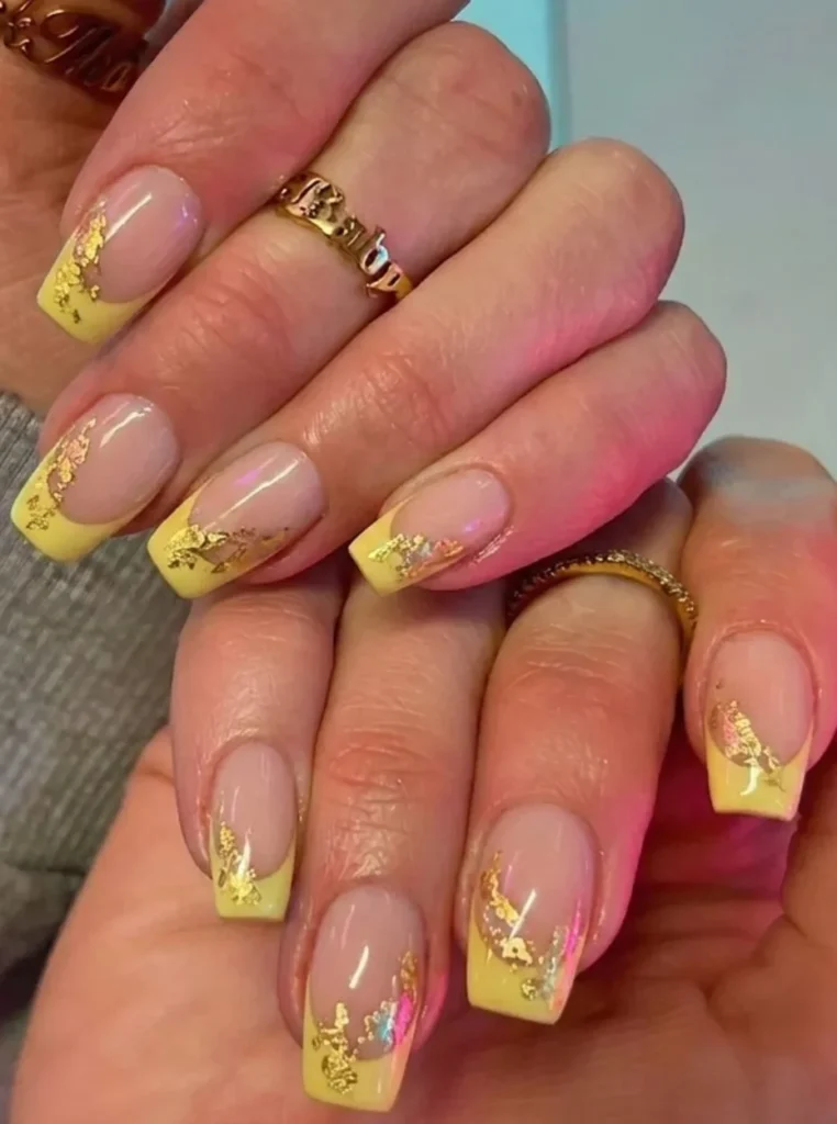Gelb French Nägel mit goldener Folie, glänzender Nude-Basis und eleganten gelben Spitzen auf eckigen Nägeln.