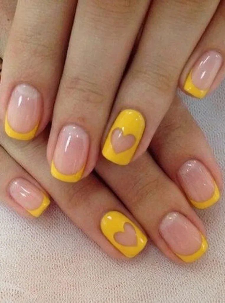 Gelb French Nägel mit süßen Herzmotiven, gelben Nagelspitzen und glänzender Nude-Basis auf kurzen eckigen Nägeln.