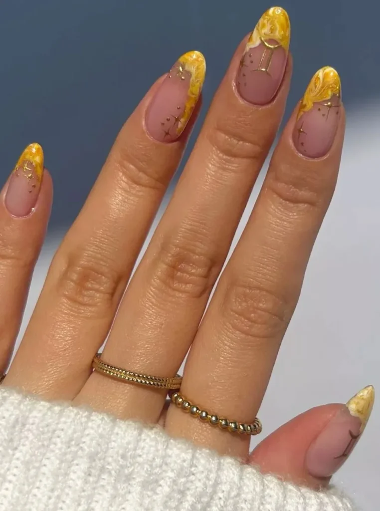 Gelb French Nägel mit elegantem Marmor-Effekt, goldenen Akzenten und glänzender Nude-Basis auf mandelförmigen Nägeln.