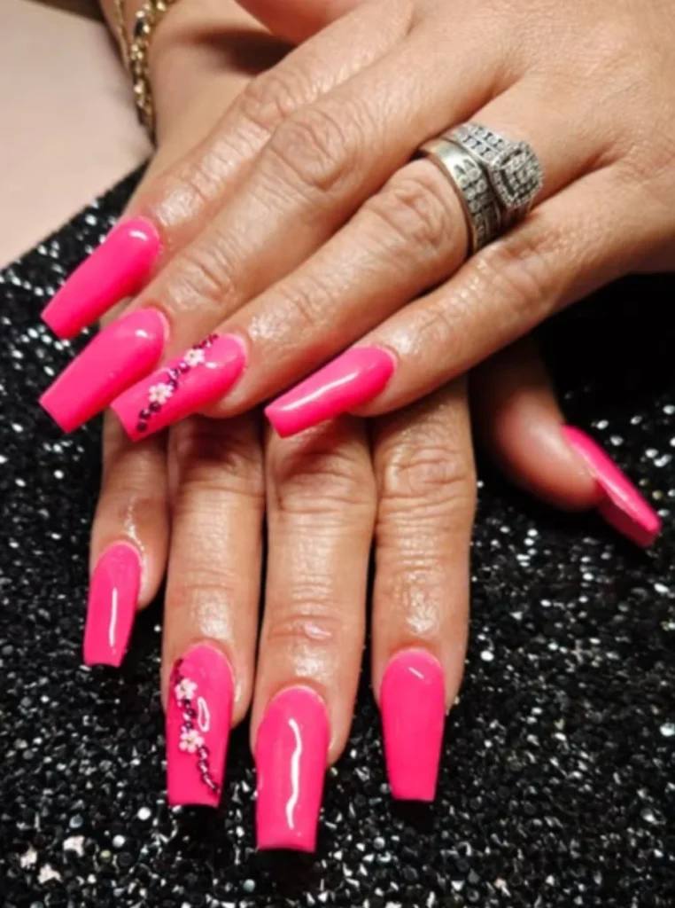 Hot Pink Coffin Nails in leuchtendem Neonpink mit glänzendem Finish und Strass-Akzenten auf langen Coffin-Nägeln.