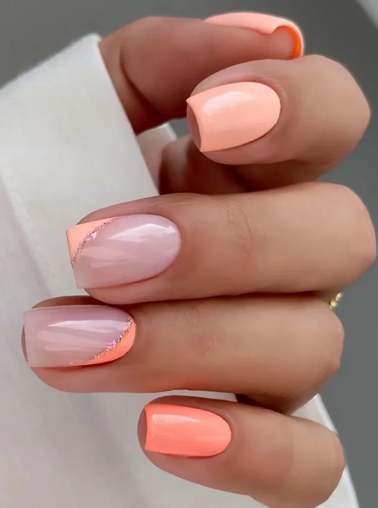 Kurze Pfirsich Nägel mit glänzendem Finish und dezenten Glitzerakzenten auf eckigen Nägeln.