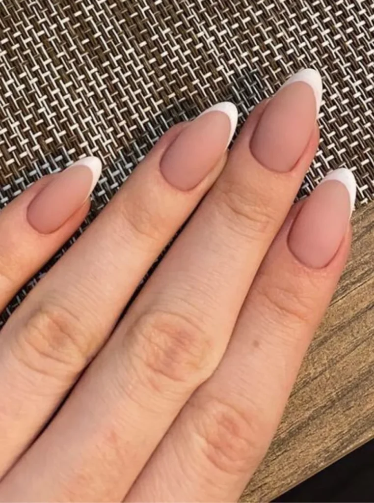 Matte French Nägel mit zarter Nude-Basis und klassischen weißen Spitzen auf mandelförmigen Nägeln für einen eleganten und zeitlosen Look.