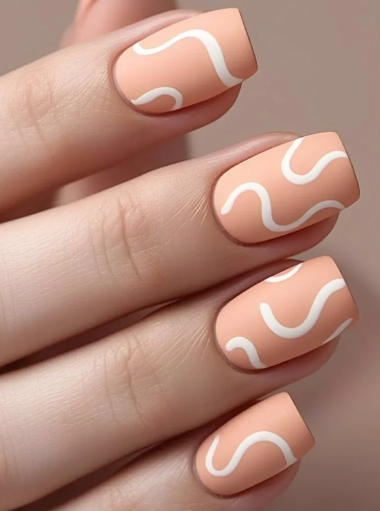 Matte Pfirsich Nägel mit weißen Wellenlinien auf eckigen Nägeln im minimalistischen Design.