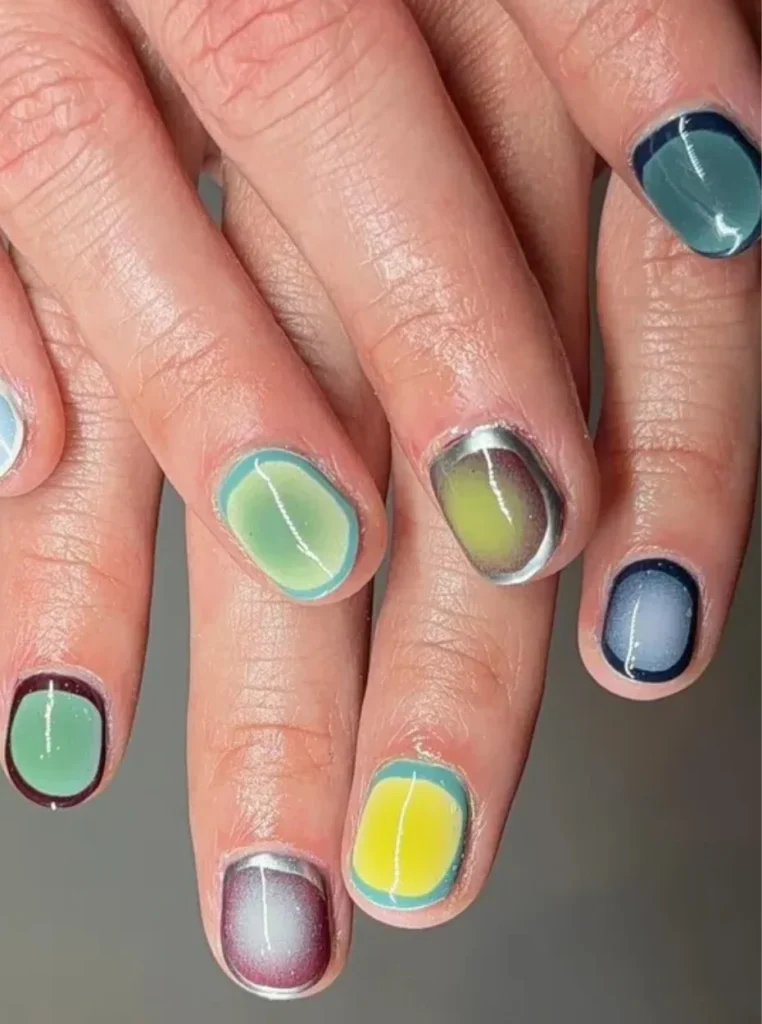 Aura Nägel in Frühlingsfarben mit sanften Farbverläufen in Blau, Grün, Gelb und Lila auf kurzen Nägeln – moderner Nageltrend Frühling 2026.