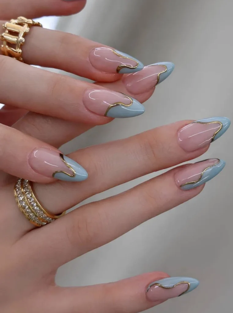 Babyblaue Nägel mit geschwungenem French Design und goldenen Linien auf mandelförmigen Nägeln – eleganter Nageltrend für den Frühling 2026.