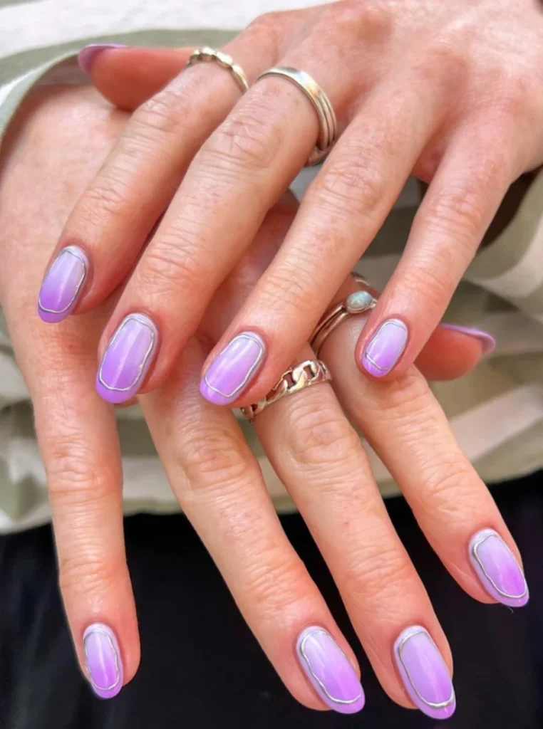 Lavendel Nails mit sanftem Ombre-Effekt und feiner silberner Kontur auf kurzen ovalen Nägeln – trendiges Frühlings-Nageldesign 2026.