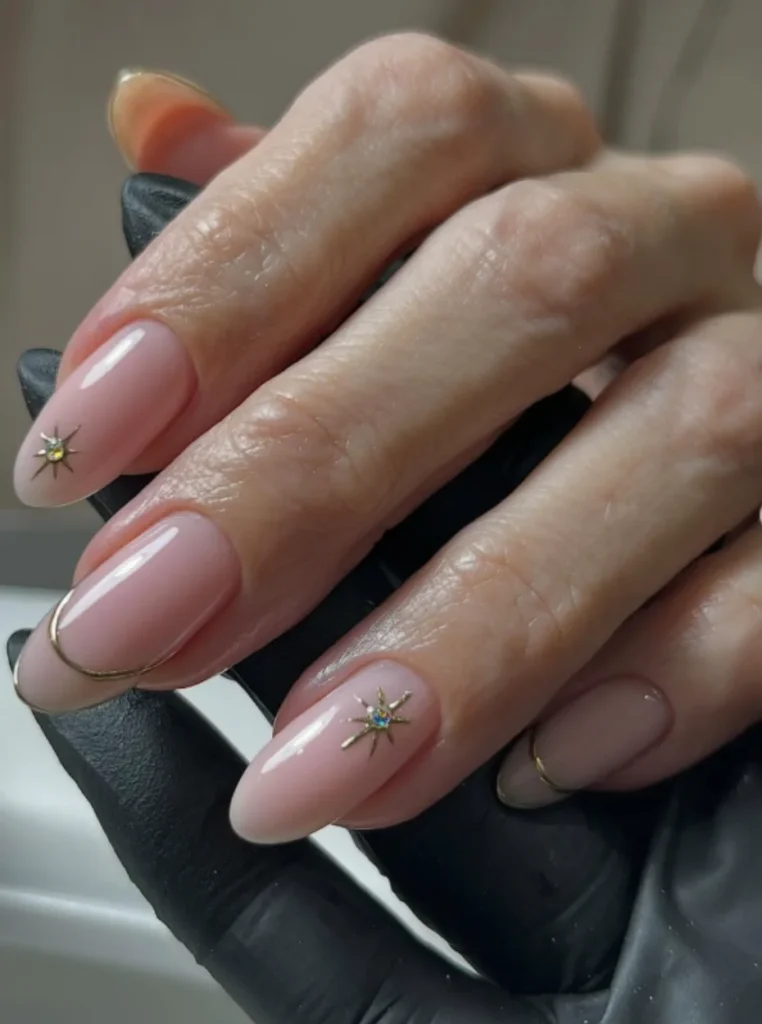 Roségold Akzentnägel mit zartem Nude-Rosa, feinen Metallic-Linien und funkelnden Stern-Details – elegantes Nageldesign für den Frühling 2026.