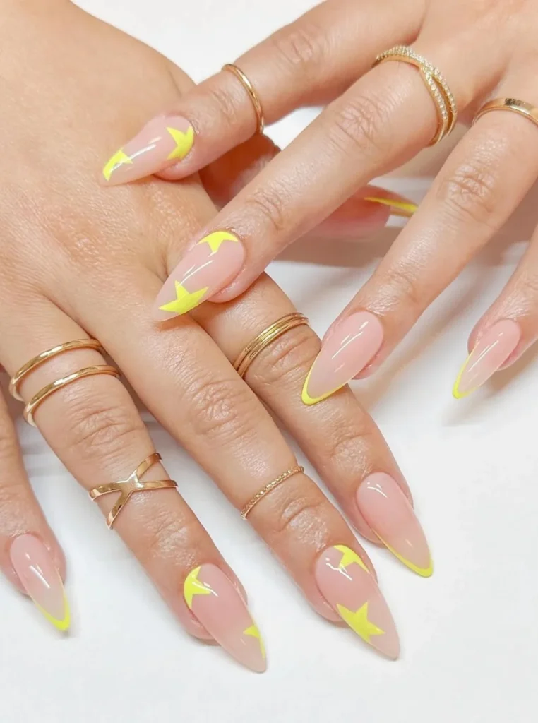 Neon gelb French Nägel mit auffälligem Stern-Design auf langen mandelförmigen Nägeln und glänzender Nude-Basis.