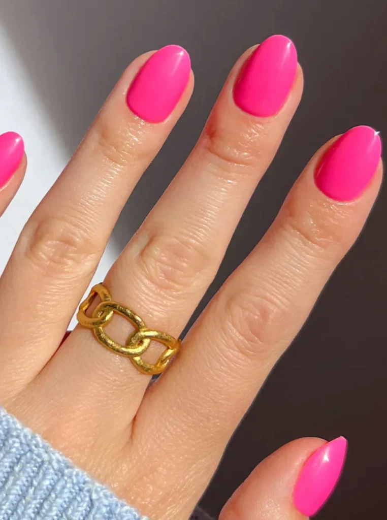 Neon Pink Nails in leuchtendem Pink mit glänzendem Finish auf kurzen ovalen Nägeln – auffälliger Sommer-Nageltrend.