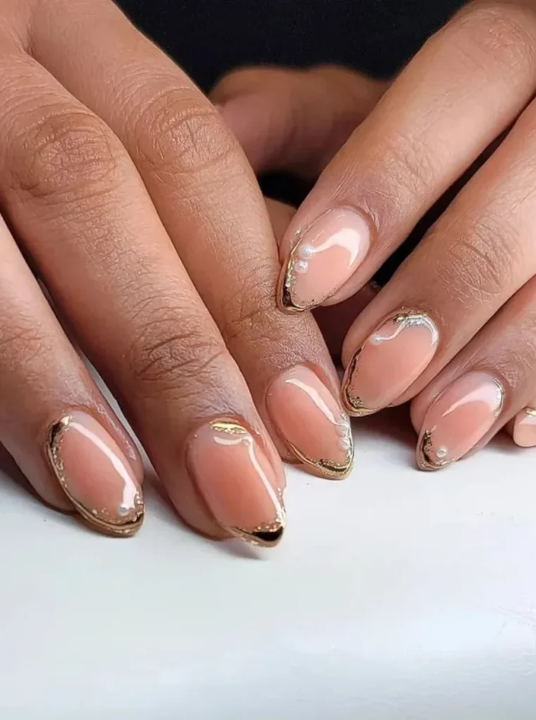 Pfirsich Nägel mit feiner Goldfolie, glänzendem Finish und eleganten Details auf mandelförmigen Nägeln.