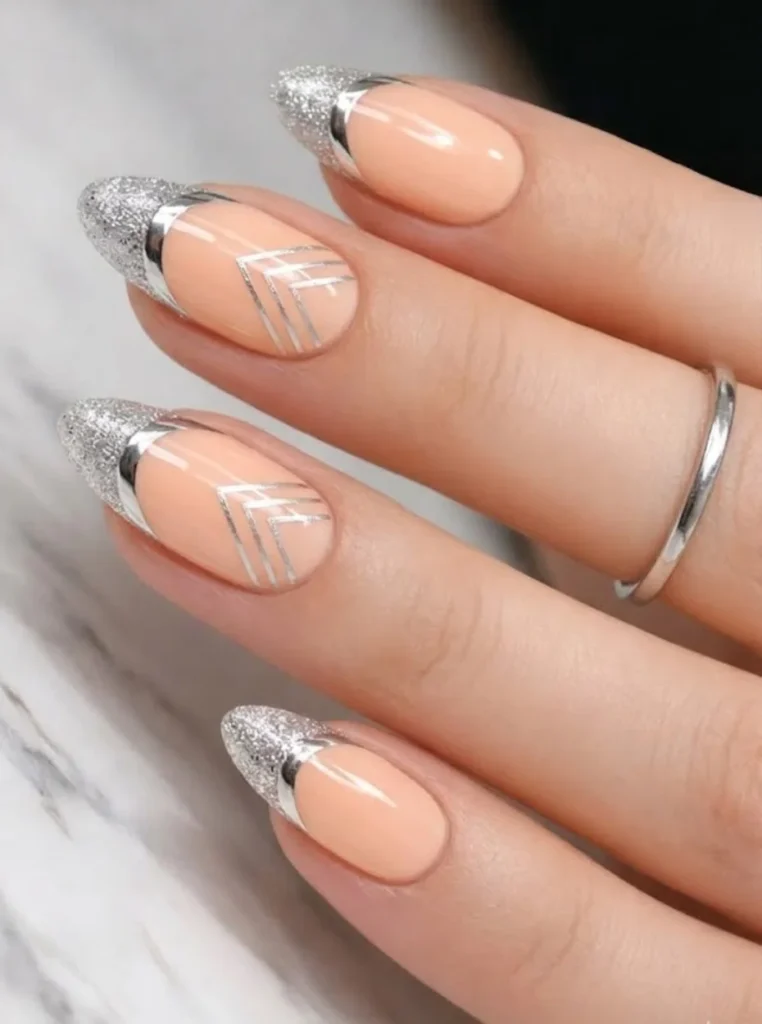 Pfirsich Nägel mit silbernen Glitzer-Spitzen und geometrischen Silberlinien auf mandelförmigen Nägeln.