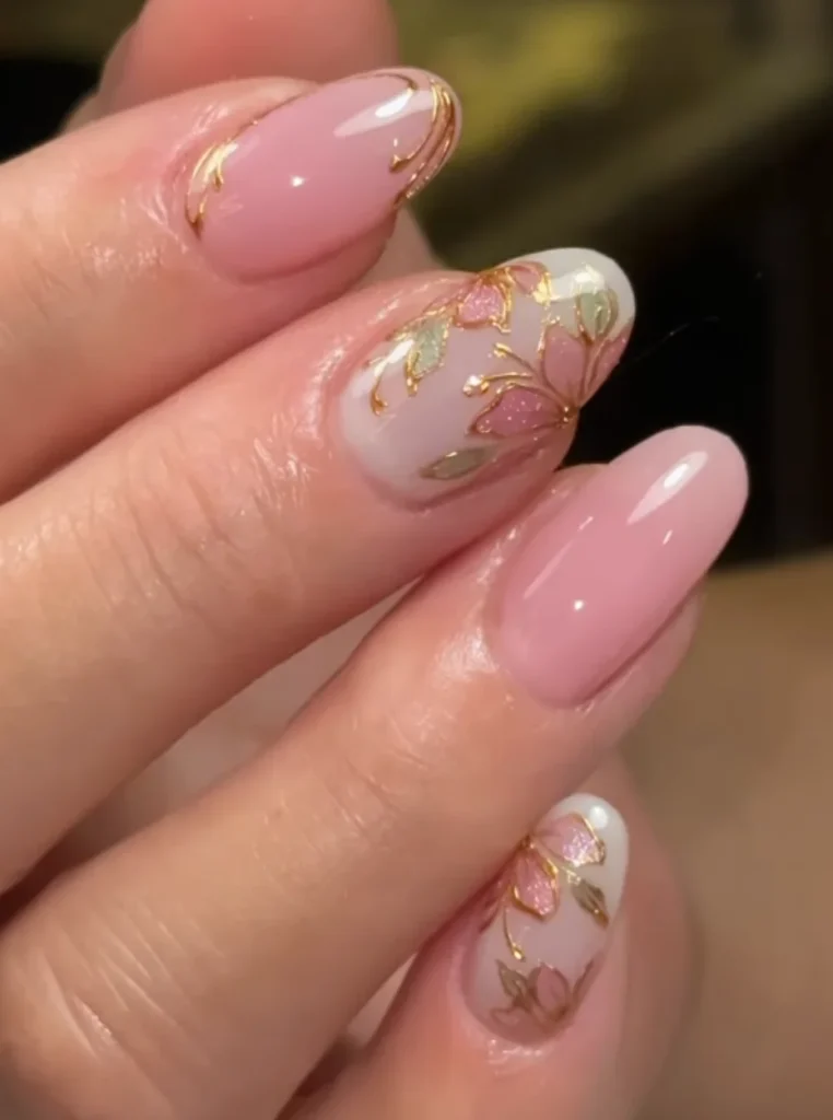 Rosa Blumen Nägel mit handgemalten Blüten, goldenen Akzenten und glänzendem Finish auf mandelförmigen Nägeln.