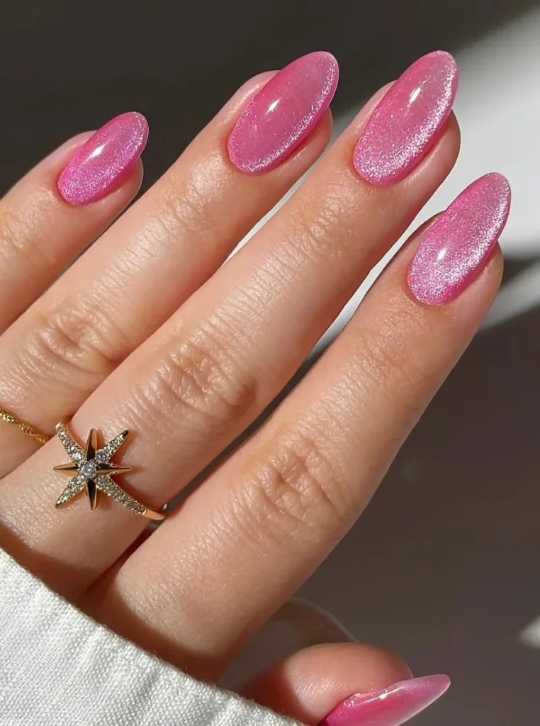 Rosa Cat Eye Nails mit schimmerndem Glitzer-Effekt und magnetischem Lichtreflex auf mandelförmigen Nägeln.