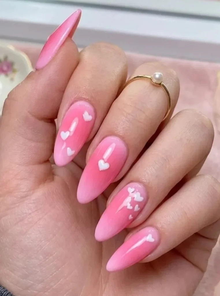 Rosa Herzchen Nägel mit weißen Herzmotiven und glänzendem Finish auf langen mandelförmigen Nägeln – romantischer Sommer-Look.