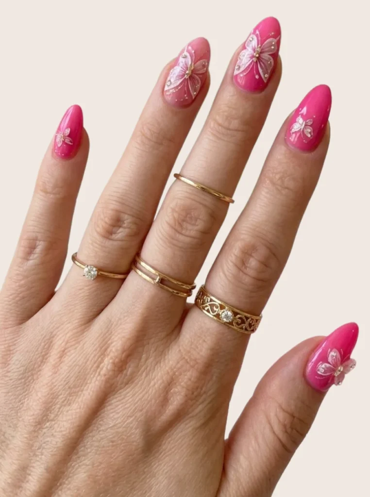 Rosa Schmetterlings Nägel mit filigranen Butterfly-Motiven, Glitzerdetails und glänzendem Finish auf mandelförmigen Nägeln.